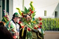 Group of people in green floral costumes walks by city street at dominican carnival