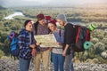 Group of people hiking and looking at map during their adventure. Two men and two women, hikers exploring mountains