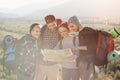 Group of people hiking and looking at map during their adventure. Two men and two women, hikers exploring mountains