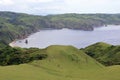 Group of people hiking the mountains around a sea surrounded by greenery under a blue sky Royalty Free Stock Photo