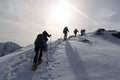 Group of people hiking on snowshoes and mountain snow panorama with summit cross in Stubai Alps