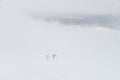 Group of people hiking in winter mountains during a snow storm, walking over clouds Royalty Free Stock Photo