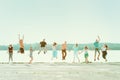 Group of people holding hands and jumping at the park near the lake. Smiling girls and boys having fun