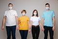 Group of people holding hands posing in medical safety mask isolated at white studio