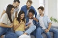 Group of people at home watching funny photos and videos together on mobile phone.