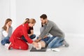 Group of people with instructor practicing CPR on mannequin at first aid class