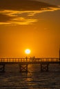 some people are walking on a pier over the water at sunset Royalty Free Stock Photo