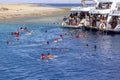 Group of people in life jackets snorkeling in the Red Sea over a coral reef, Dahab, Egypt