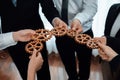 Group of people making chain of gears into collective form for harmony symbol.