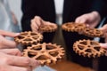 Group of people making chain of gears into collective form for harmony symbol.