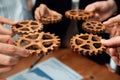 Group of people making chain of gears into collective form for harmony symbol.