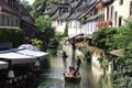 Group of people with mask on wooden boat with tourist guide sailing through romantic canal.