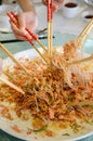 A group of people mixing and tossing Yee Sang dish with chop sticks. Royalty Free Stock Photo