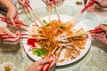 A group of people mixing and tossing Yee Sang dish with chop sticks. Yee Sang is a popular delicacy taken during Chinese New