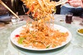 A group of people mixing and tossing Yee Sang dish with chop sticks. Yee Sang is a popular delicacy taken during Chinese New