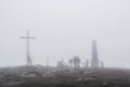 Group of people near cross and monument in the fog Royalty Free Stock Photo