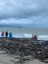 A group of people observing storm aftermath on Nha Trang beach covered with scattered debris and branches under light Royalty Free Stock Photo