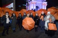 Group of people outdoor holding orange umbrellas in hands. Flashmob dedicated to International Day for Elimination of