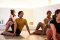 A group of people are practicing ardha matsyendrasana yoga pose in a room. Royalty Free Stock Photo
