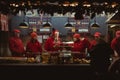 Group of people in red uniforms in front of a table in a Hot dog stall at a Christmas market Royalty Free Stock Photo