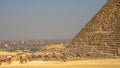 Group of people riding camels in front of a pyramid