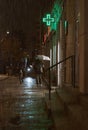 Group of people are seen walking down a wet and slick sidewalk during a rain shower.