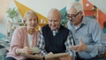 Group of people senior men and woman watching pictures in album talking having fun