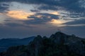 Group of people silhouetted against a vibrant sunset on a hilltop with a cross