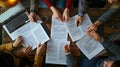 A group of people are sitting around a table with papers and laptops Royalty Free Stock Photo