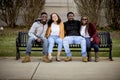 Group of people sitting on a bench in a park under sunlight with a blurry background Royalty Free Stock Photo