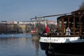 A group of people sitting on the deck of a restaurant boat moored on the shore overlooking the historic centre of Prague, Czech