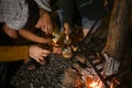 Group of people sitting near burning bonfire and drinking some beer while camping on weekend holiday.