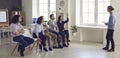 Woman in audience raises hand to ask question during meeting with business coach in office Royalty Free Stock Photo