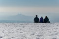 People sitting in snow and watching winter landscape panorama