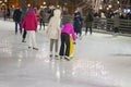 Group of people skating back to us. Family vacation with kid ice skating in city park, outdoor winter activity