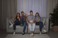 Group of people with snacks watching TV together on couch