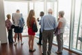 Group of people standing on an upper level floor of high-rise building talking with outlook to city view below