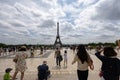 Group of people strolling down a sidewalk in front of the iconic Eiffel Tower in Paris, France