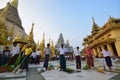 A group of people suddenly together sweep the floor in one long line in Shwedagon Pagoda