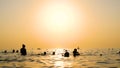 A group of people swimming in the sea on the beach at sunset. Royalty Free Stock Photo