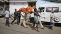 a group of people are taking a dead body to the Ganges to prepare for cremation