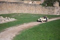 Group of people traveling down a path by an old stone wall