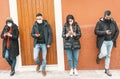 Group of people using their smart phones during coronavirus pandemic protected with face mask - Friends standing by the wall with Royalty Free Stock Photo