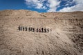 a group of people walk up the side of a dirt hill