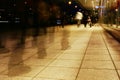 A group of people walking along the sidewalk promenade long exposure at night