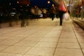 A group of people walking along the sidewalk promenade long exposure at night