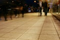 A group of people walking along the sidewalk promenade long exposure at night