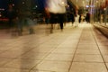 A group of people walking along the sidewalk promenade long exposure at night