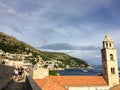 A group of people walking along the Walls of Dubrovnik with the Adriatic sea glistening in the background, in Dubrovnik, Croatia.