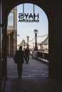 Group of people walking on the city sidewalk, beneath a building with a sign reading 'Hays Gallery'